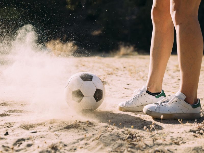 crop athletic legs standing by football outdoors